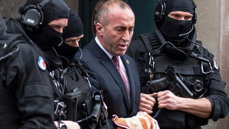 Former prime minister of Kosovo Ramush Haradinaj, center, leaves the court escorted by hooded police officers in Colmar, eastern France