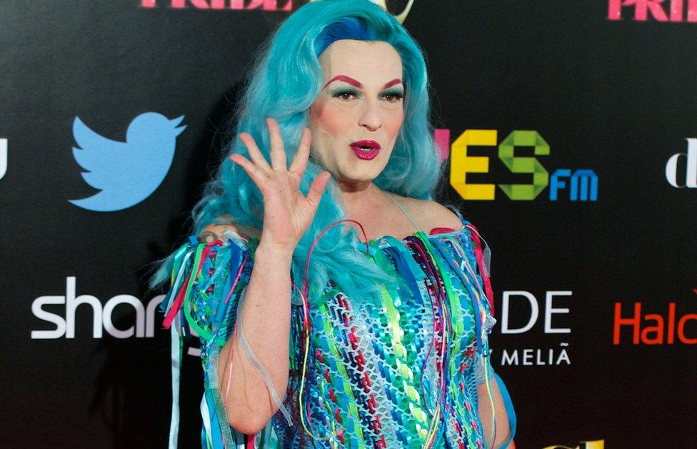 Spanish singer Amapola Lopez - known as 'La Prohibida' - waves for the cameras in a blue dress that matches her blue hair