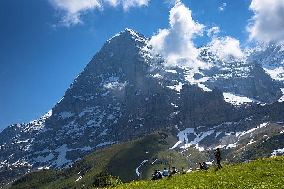 Tourists stand next to a mountain