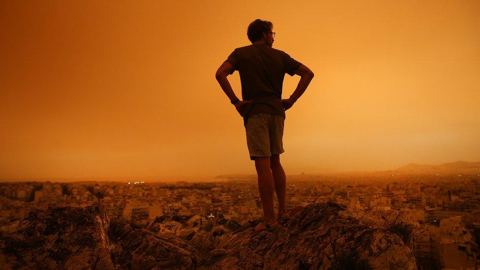 man-staring-at-orange-dust-storm-in-athens.