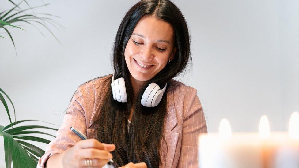 Stock shot of woman writing with candles in foreground