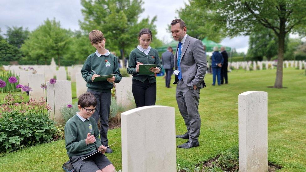 Children writing memories in front of war graves