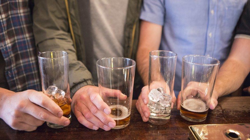 Four nearly empty glasses of alcohol on a pub bar