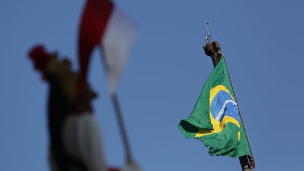 A soldier of the presidential guard stands at attention as the flag of Brazil flies in the background, in front of the Planalto Presidential Palace, in Brasilia (12 April 2016)