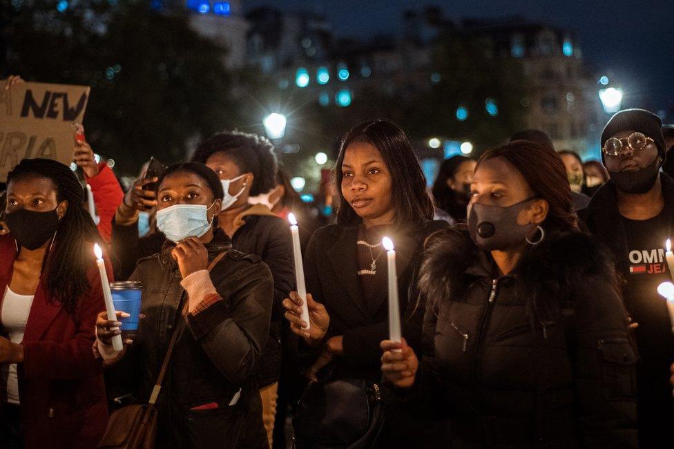 People in Trafalgar Square in London hold a candlelight vigil