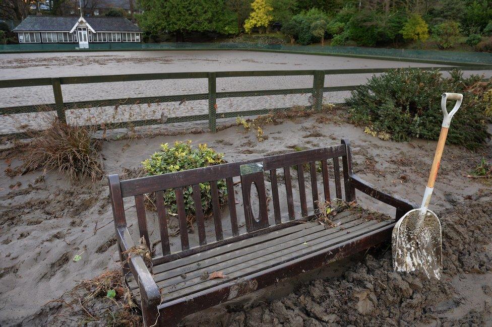 A shovel is left by a park bench as silt covers the bowling green in Fitz park after the river Greta flooded in Keswick