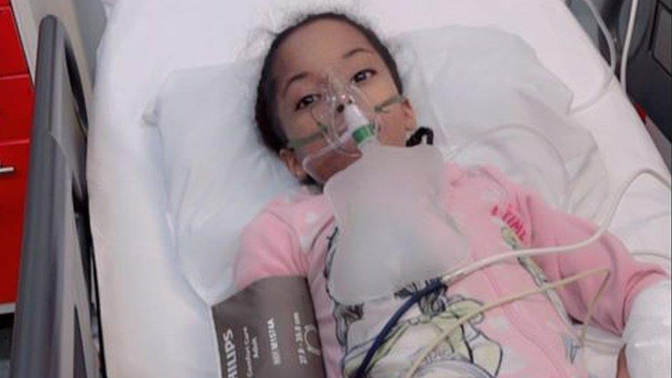 A little girl in a hospital bed with ventilator