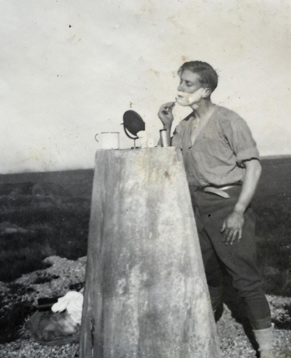 Man shaving on trig pillar