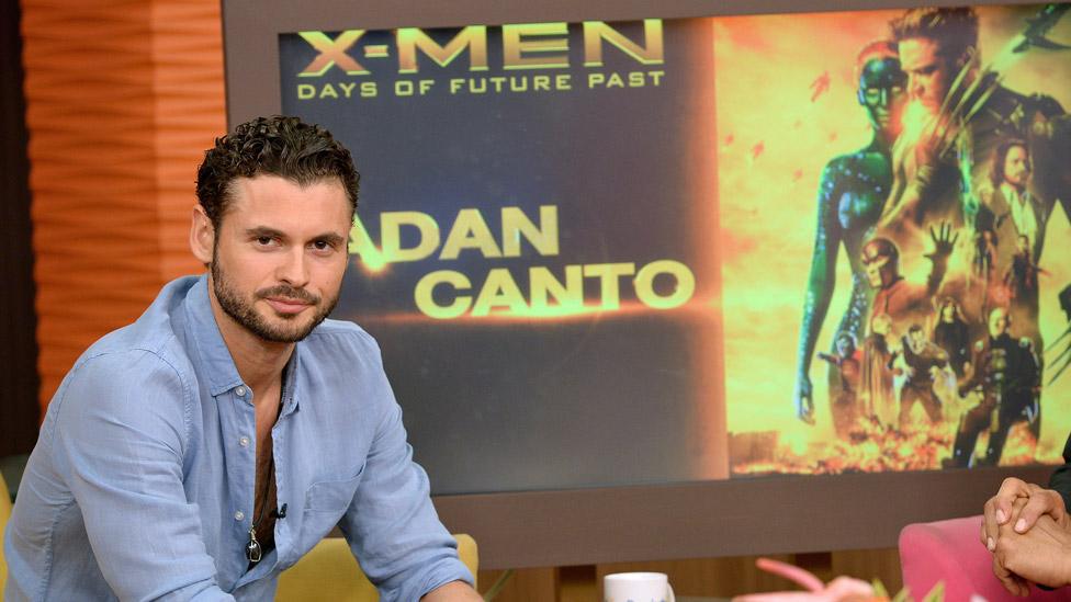 Adan Canto in front of a screen showing his name and a poster image for X-Men: Days of Future Past