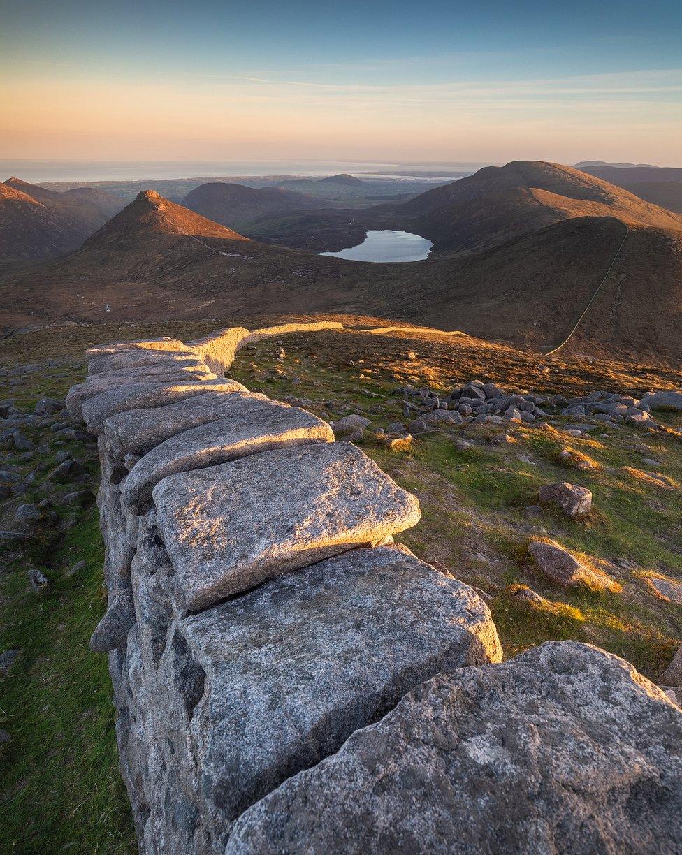 Sunset over the Mourne wall leading to Slieve Doan and Carn mountain as seen from Slieve Loughshannagh in the Mourne mountains in County Down