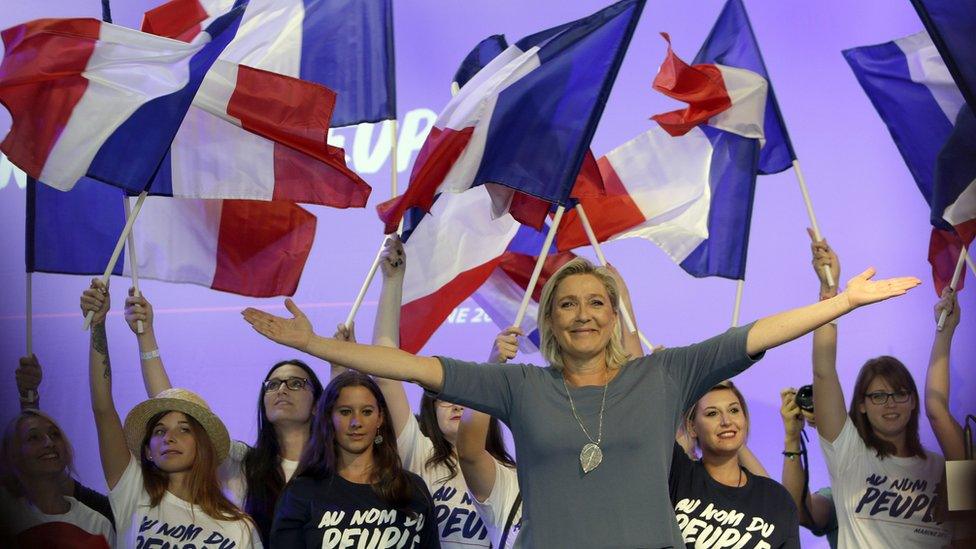 Marine le Pen in front of people waving flags