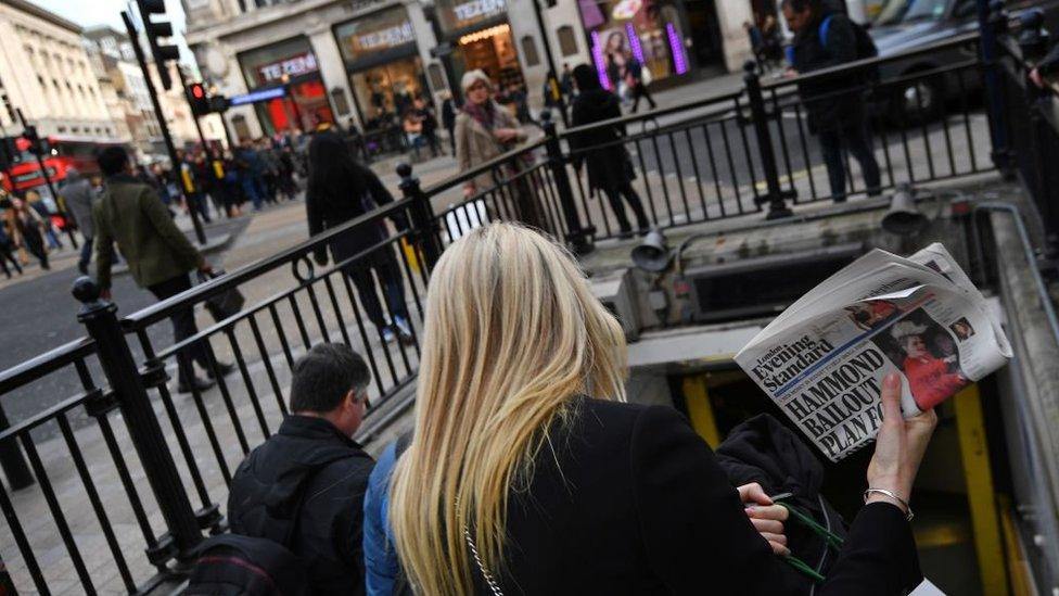 A woman carries a copy of the Evening Standard newspaper