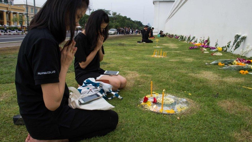 Thai women follow Buddhist prayers on their mobile phones outside the Grand Palace in Bangkok 16 October