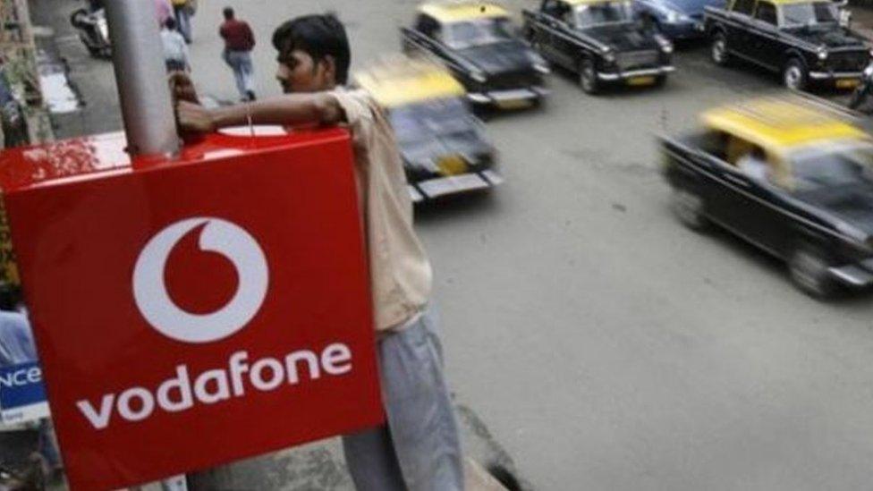 A worker adjusting a Vodafone sign in India