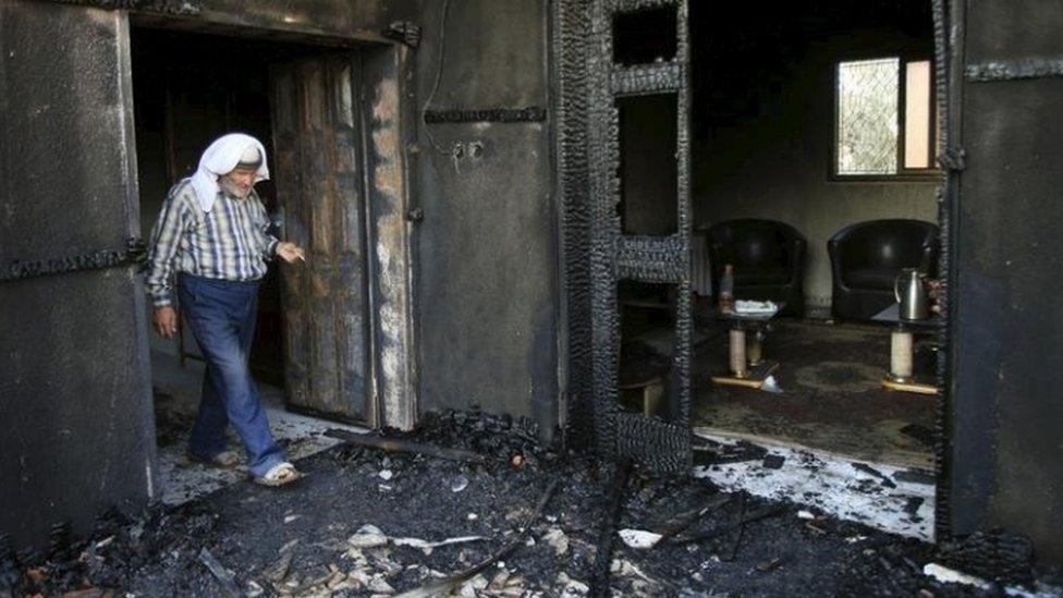 A man looks through the badly burnt house of a Palestinian family