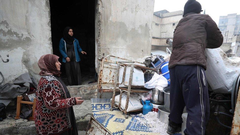 A displaced Syrian woman watches as her belongings are unloaded at a makeshift camp in opposition-held Idlib province, Syria (31 December 2019)