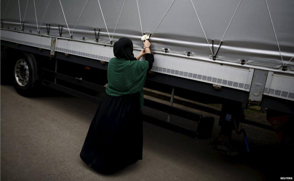 A woman places a flower on a truck carrying 136 coffins of newly identified victims of the 1995 Srebrenica massacre, in the village of Visoko,Bosnia and Herzegovina, July 9, 2015.