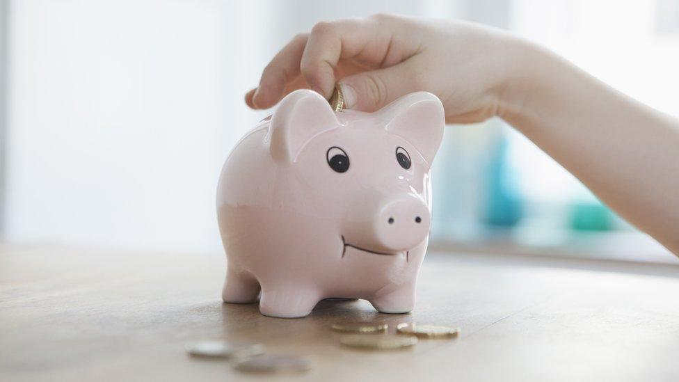 Hand putting coins into piggy bank