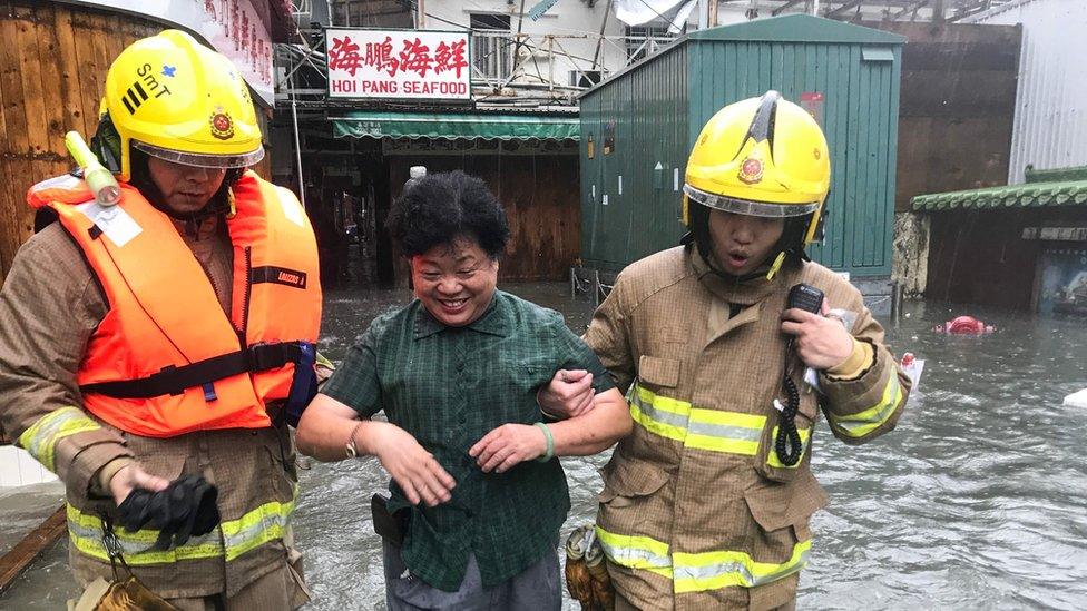 Fire rescue workers rescue a woman in floodwaters in the village of Lei Yu Mun during Super Typhoon Mangkhut in Hong Kong on 16 September 2018.