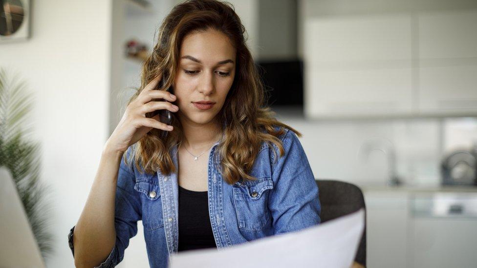 Women on the phone looking stressed at a bill