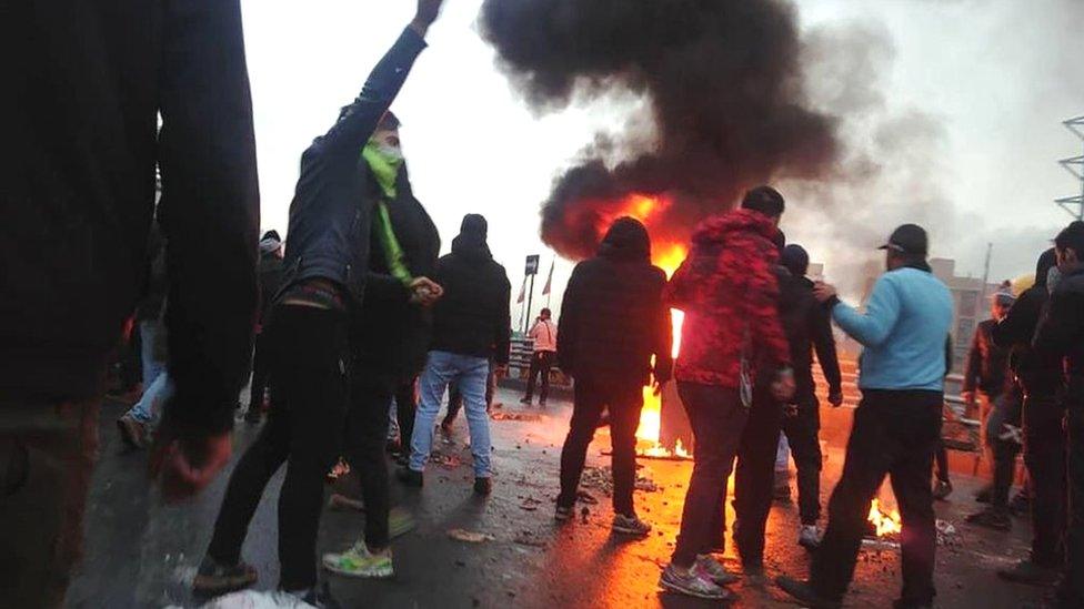 Iranian protesters gather around a fire during a demonstration against an increase in petrol prices in Tehran (16 November 2019)