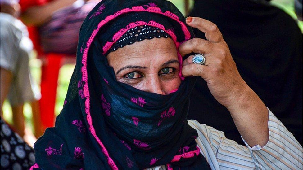 A member of the transgender community wearing a face mask waits to receive the COVID-19 vaccine at a park in Srinagar