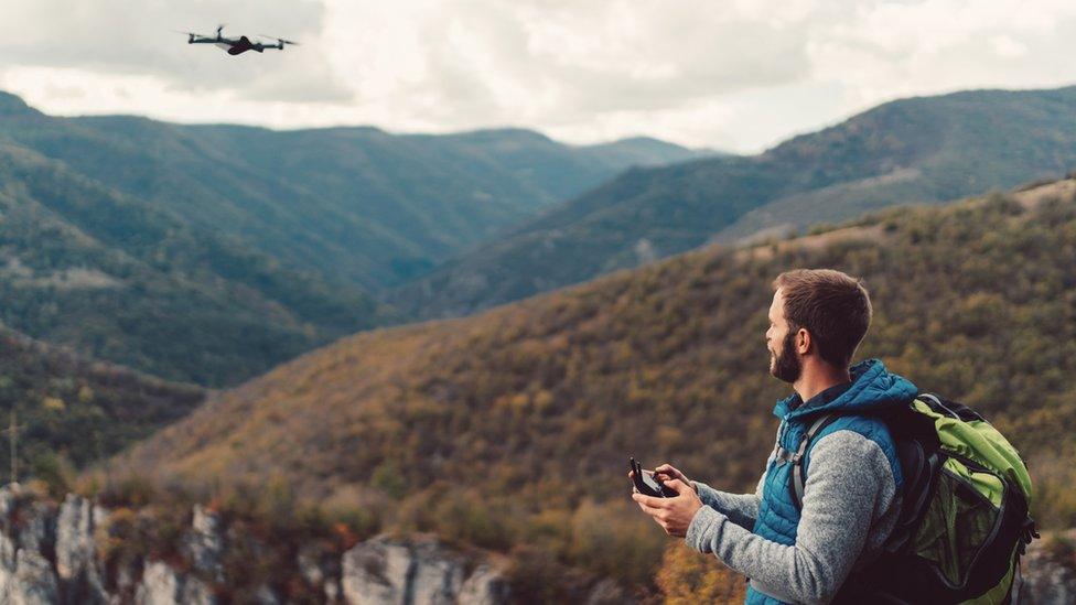 A man flying a drone on a mountain top