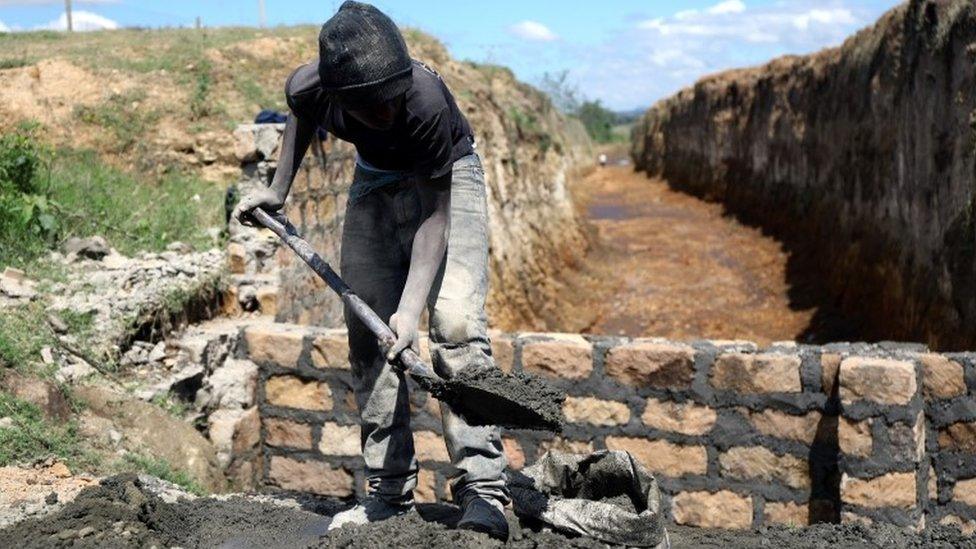 A man mixes mortar as he repairs a bridge broken by flooding waters near the Rift Valley town of Mai Mahiu, Kenya November 27, 2019