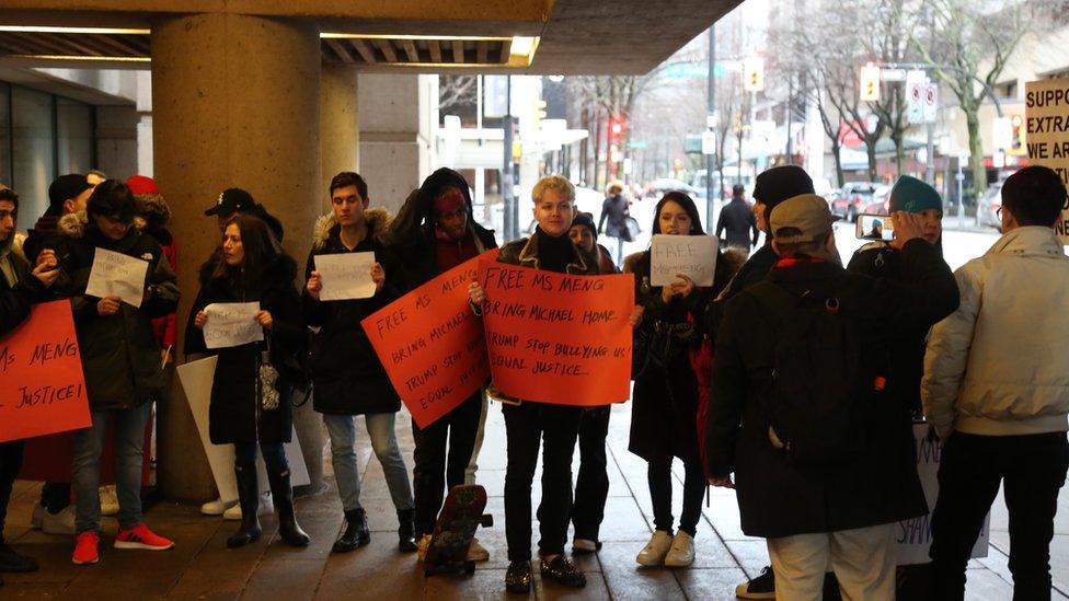 People hold placards reading "Free Ms Meng" outside court on day one Meng Wanzhou's extradition hearing