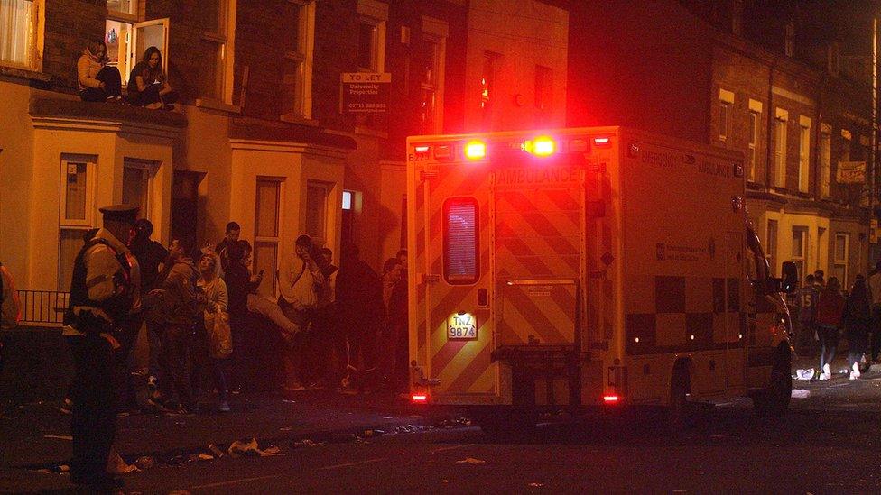 An ambulance, a police officers and a crowd of revellers in the Holyland