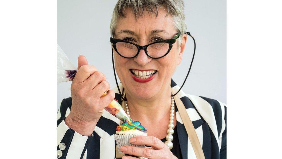 Karen smiles while icing a rainbow cupcake