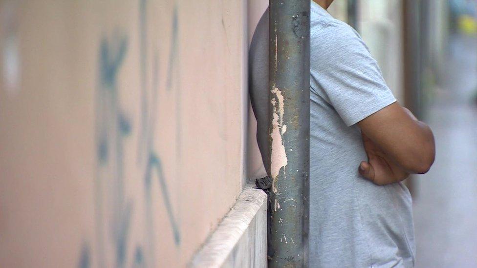 A migrant boy standing next to a wall in Rome