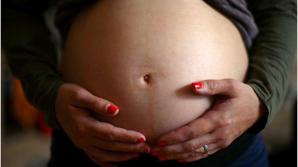 A pregnant woman holding her stomach in London.