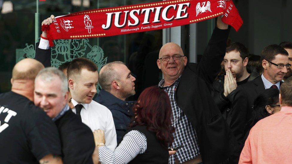 Hillsborough campaigners holding a Liverpool scarf that reads "justice".