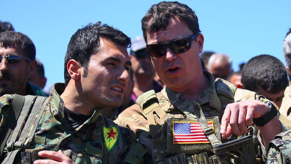 A US officer, from the US-led coalition, speaks with a fighter from the Kurdish People's Protection Units (YPG).