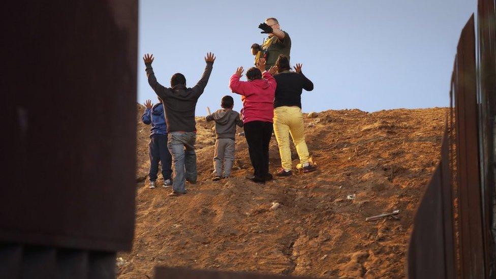 Migrants from Honduras put their hands in the air as they surrender to a U.S. Customs and Border Protection (CBP) official in San Diego County, U.S