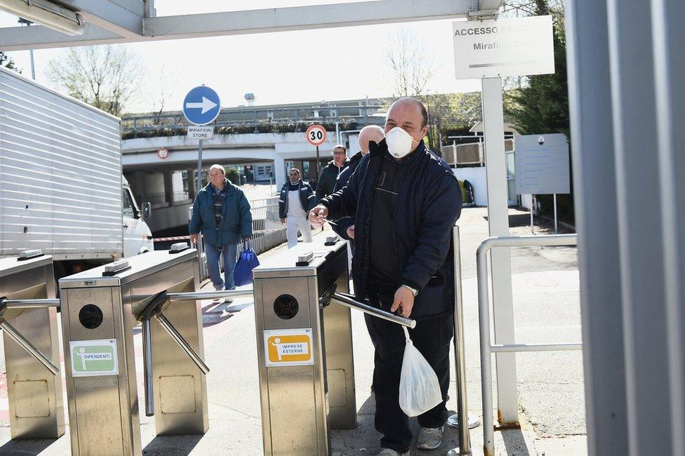 A man walks through a turnstile whilst wearing a face mask