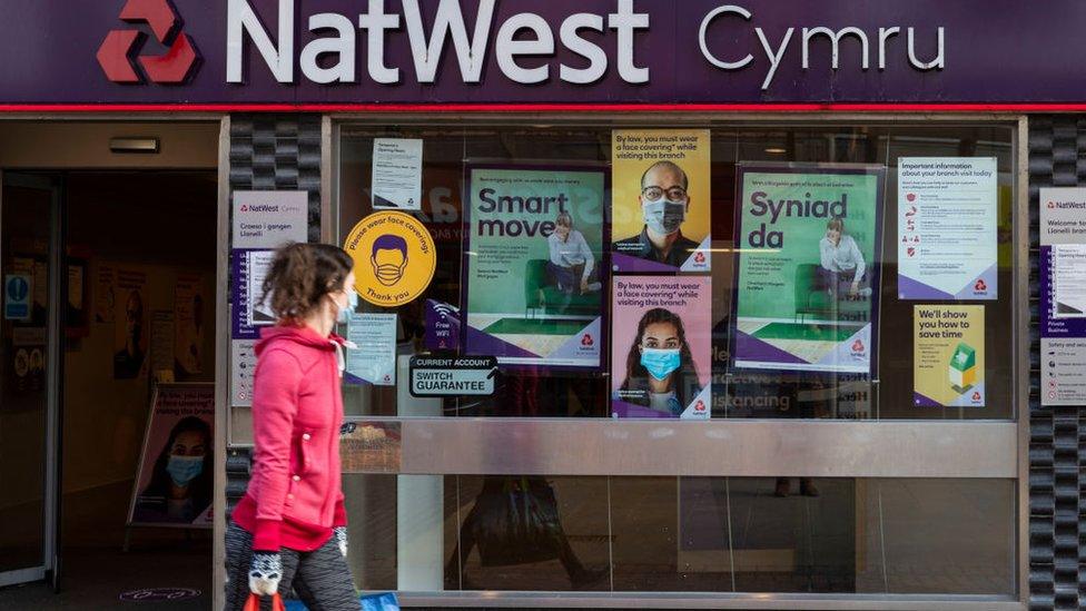 Woman walks past a NatWest brancj