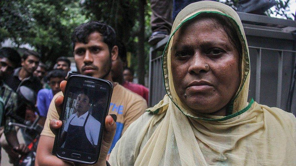 A woman named Johra shows a mobile phone picture of her brother-in-law Saidul, a restaurant employee