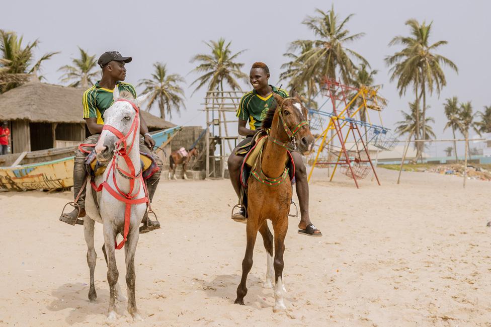 Two men riding horses on the beach