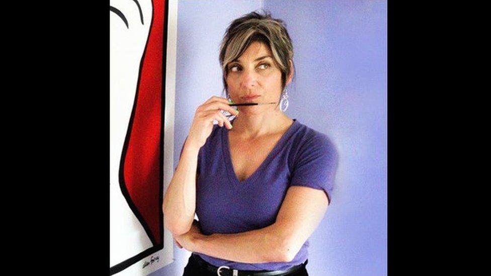 Ellen Forney posing with a paintbrush in hand