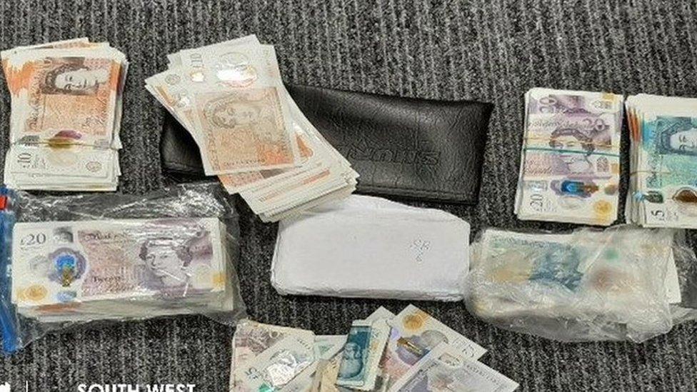 A wallet and a load of folded cash on a table