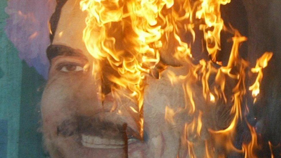 A poster of Iraqi President Saddam Hussein burning in Baghdad (14 April 2003)