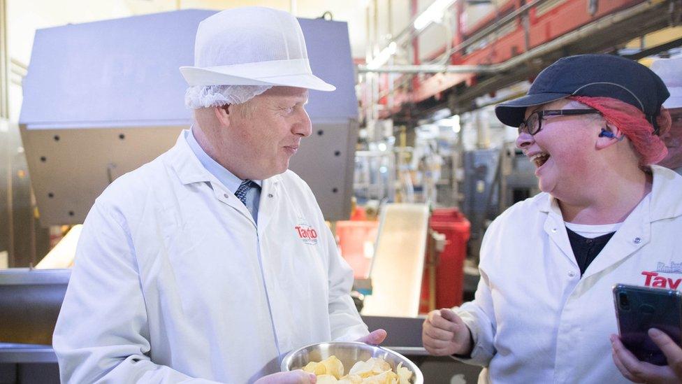 A worker appears to be asking for a photo with Boris Johnson while they both smile