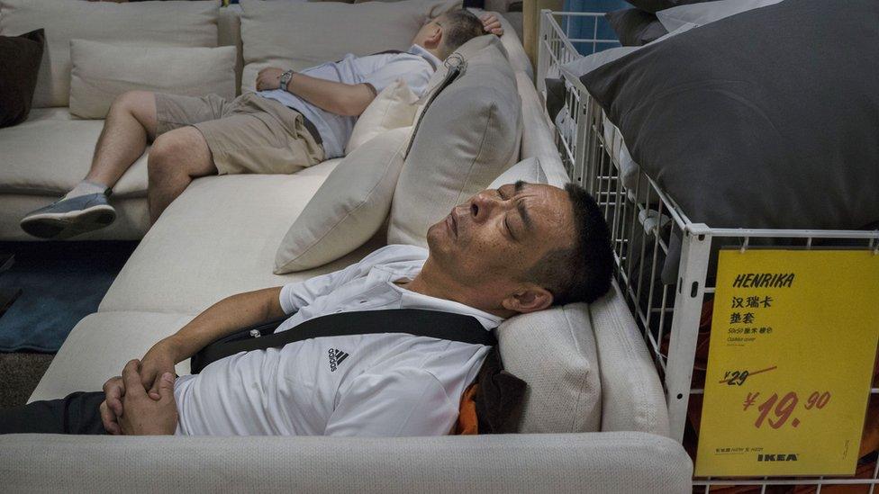 Chinese shoppers sleep on a sofa in an Ikea showroom