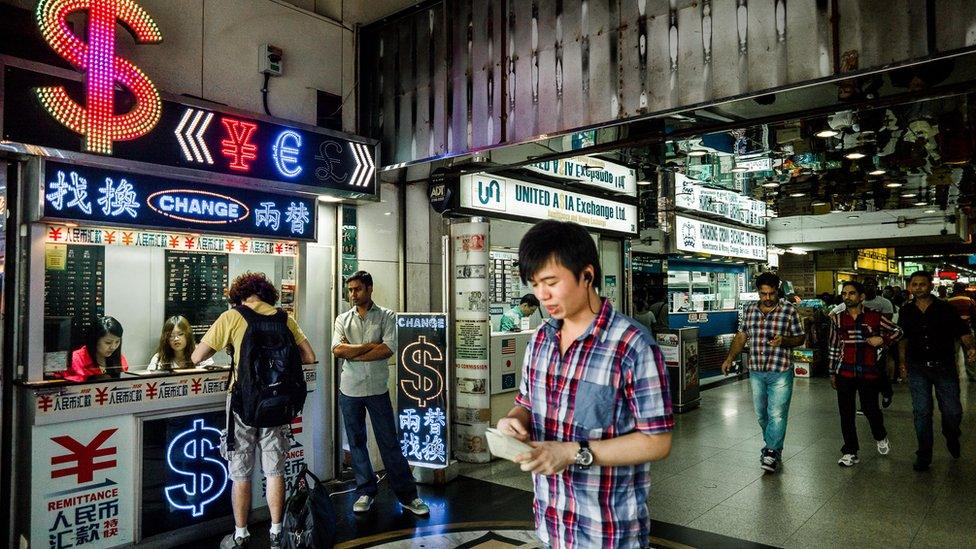 File photo: A man walks past a currency exchange booth in Hong Kong on October 24, 2012