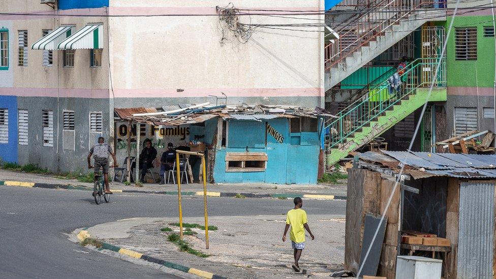 Police sit at a street corner in Denham Town