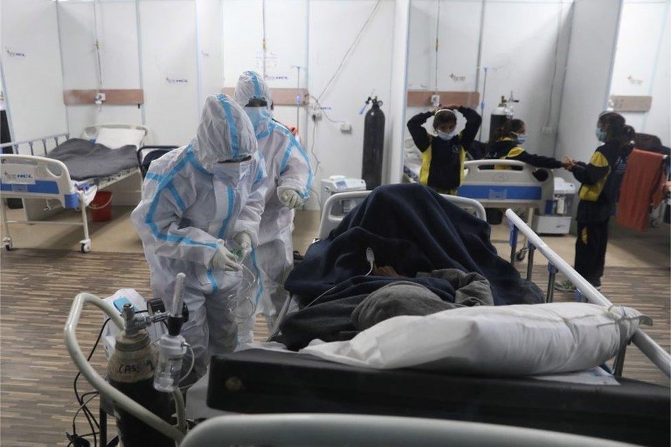 Indian medical professionals wearing Personal Protective Equipment (PPE) attend to patients inside a Covid-19 care centre and isolation ward facility, in an indoor stadium inside Commonwealth Games (CWG) Village sports complex in New Delhi, India, 04 January 2022