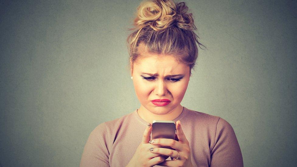 Woman looking unhappily at mobile phone