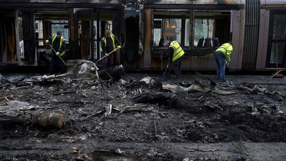 Debris is cleared from a burned out Luas and bus on O'Connell Street in Dublin, in the aftermath of violent scenes in the city centre on Thursday evening